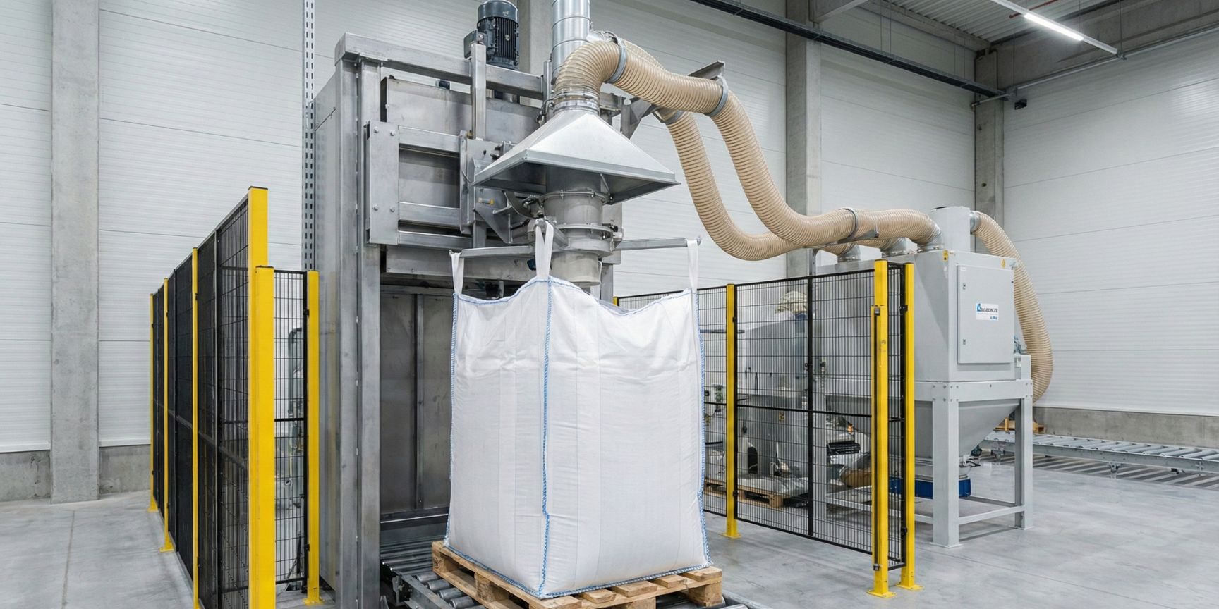 Automatic big bag filling system in a logistics hall. A white Q-Bag (dimensionally stable big bag) is filled on a pallet, while an extraction system provides dust protection.